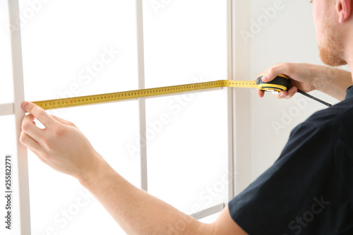 Service man measuring window for installation indoors, closeup