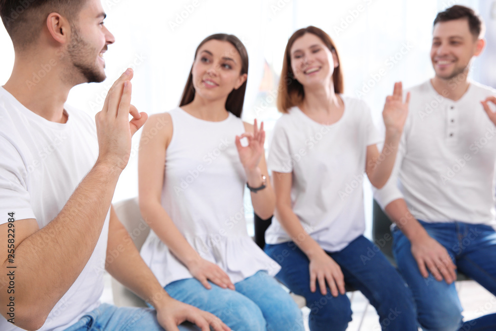 Obraz premium Group of young people learning sign language with teacher indoors