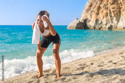 Beautiful sporty young woman tired after workout on the beach