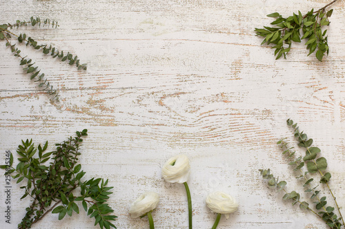 Beautiful ranunculus flowers among herbs on wooden background