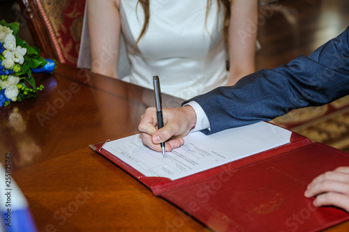 The groom puts his signature on the documents of marriage in the Palace of marriage