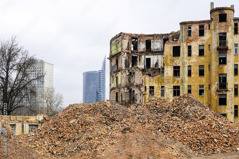 demolition of a large old historic stone house in the city, new multi-storey buildings in the background