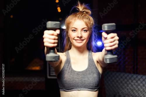 Blonde woman with dumbbells in hand in training. © snedorez