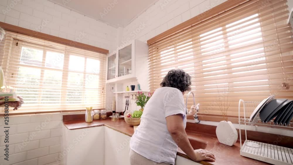 Asian elderly couple man holding cake celebrating wife's birthday in kitchen at home. Chinese couple enjoy love moment together at home. Lifestyle senior family at home concept.