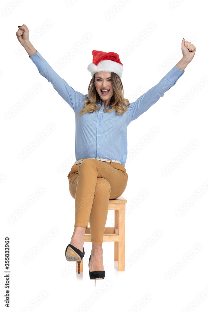 Cheering young businesswoman wearing santa hat Cheering young businesswoman wearing santa hat
