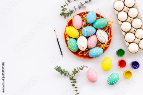 Colorful Easter eggs and paint for celebration on white background top view mock up