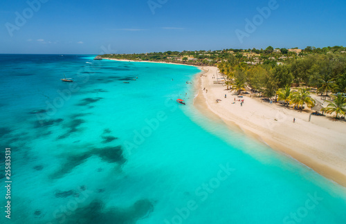 Fototapeta Naklejka Na Ścianę i Meble -  Aerial view of boats on tropical sea coast with sandy beach at sunny day. Summer holiday on Indian Ocean, Zanzibar, Africa. Landscape with boat, palm trees, transparent blue water, hotels. Top view