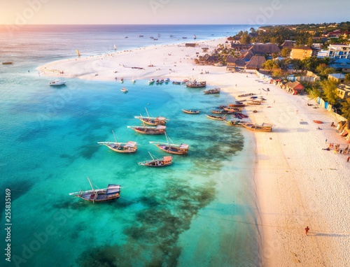 Foto Aerial view of the fishing boats on tropical sea coast with sandy beach at sunset