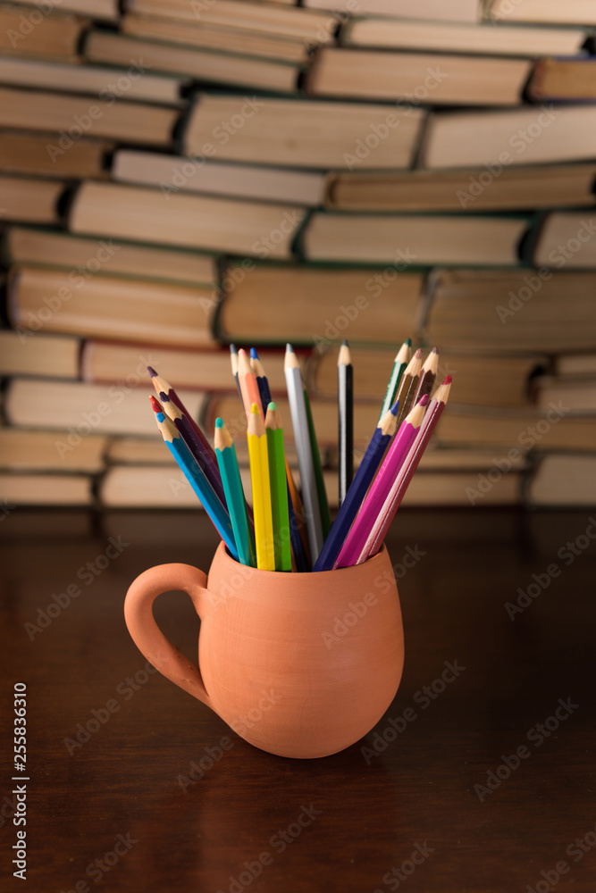 colored pencils in a mug and many books on the desktop colored pencils in a mug and many books on the desktop