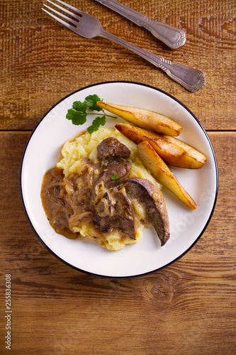 Liver with pears and cream and wine onion sause on mashed potato. overhead, vertical