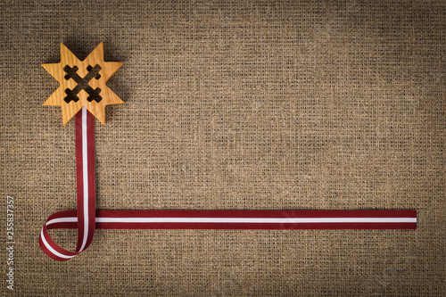Foto National composition of latvian flag ribbon and wooden symbol Auseklis