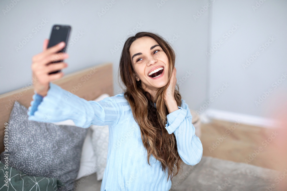 Young woman taking selfie while sitting on sofa at home. Young woman taking selfie while sitting on sofa at home.