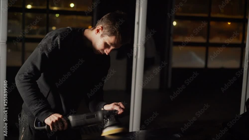 Car detailing - Hands with orbital polisher in auto repair shop. Polished black car. Car detailing - Hands with orbital polisher in auto repair shop. Polished black car.