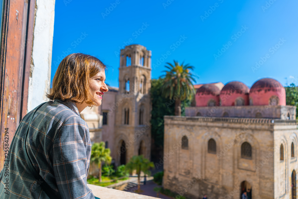 handsome tourist girl traveling in Palermo and watching Piazza Bellini Square, the Santa Maria dell'Ammiraglio Church known as Martorana Church and San Cataldo from the window