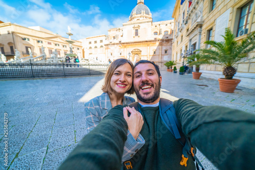 happy tourist couple traveling in Palermo, Sicily and taking selfie in Famous fountain of shame on baroque Piazza Pretoria, Palermo, Sicily, Italy. Italian holidays road trip photo