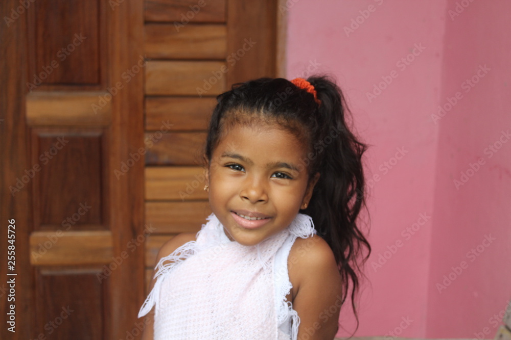 Portrait of cute little girl. She's got your old wooden door. African-American mixed race child.