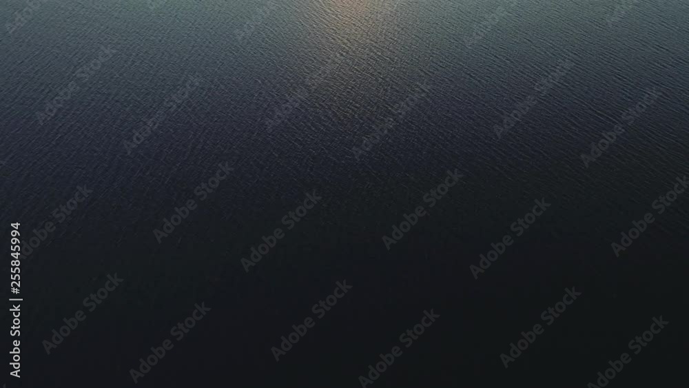 Aerial shot pans up from ocean to reveal magnificent water landscape at sunset. shot in Canada, beautiful sky and mountains in distance.