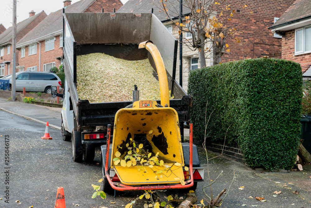 An enginepowered drum woodchipper towed behind a tipper dump truck
