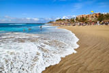 View of the sandy beach of Playa del Duque with a beautiful wave in the popular resort Costa Adeje on the southern coast of Tenerife. Canary Islands, Spain.