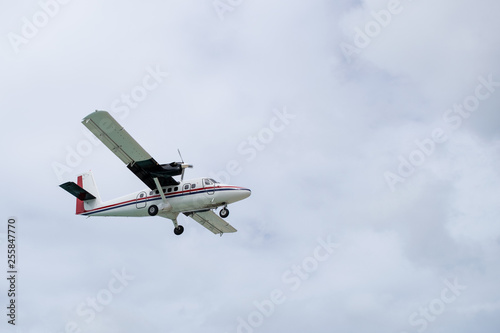 White twin otter DHC-6 aircraft with wheels down, preparing for landing