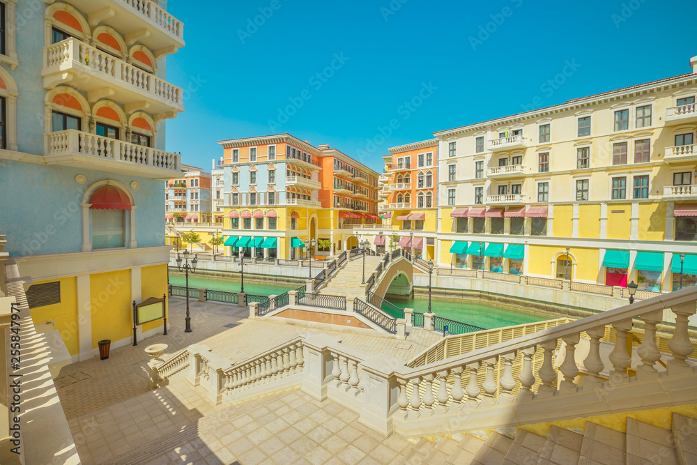 Large staircase leading to a Venetian bridge on canals of picturesque Qanat Quartier icon of Doha, Qatar in a sunny day with blue sky. Venice at the Pearl-Qatar, Persian Gulf, Middle East.
