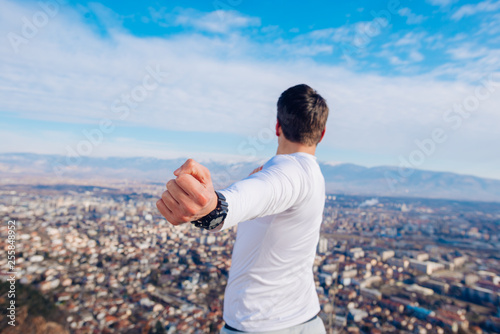 A young strong fit masculine man working out in the morning while looking at the city.