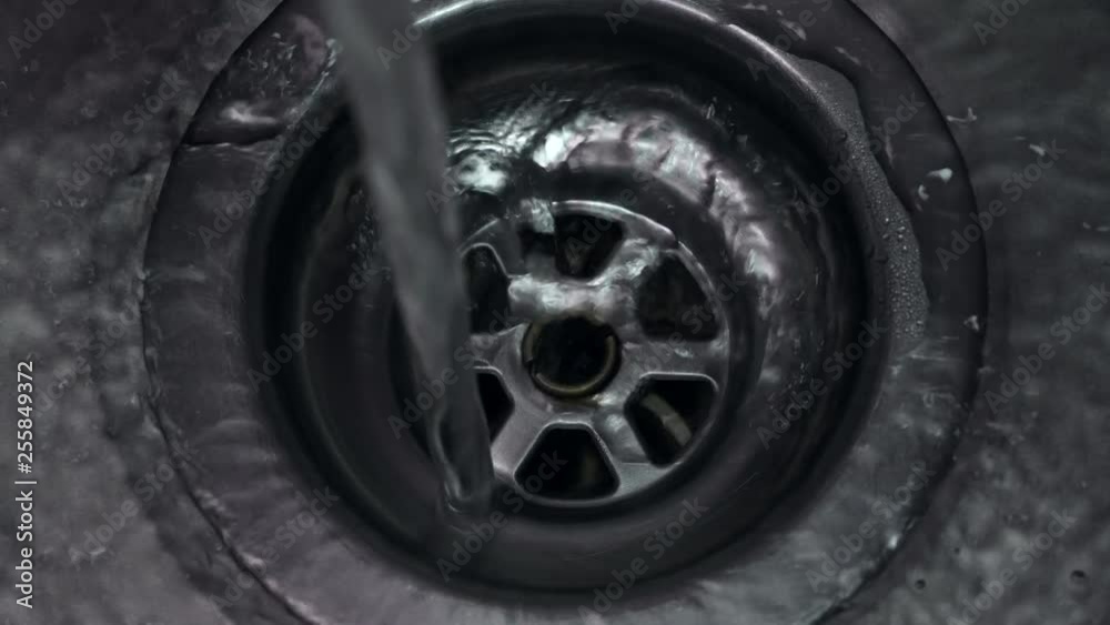 Top down view of clear fresh water running down plug hole in stainless steel sink. Fast shutter speed. Top down view of clear fresh water running down plug hole in stainless steel sink. Fast shutter speed.