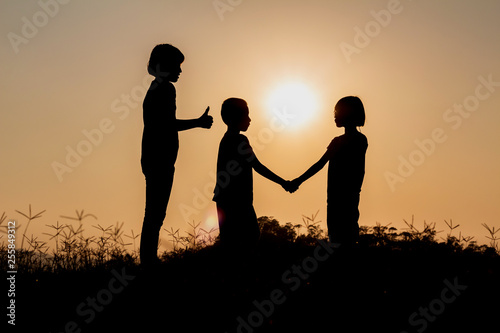 Silhouette group children playing on meadow at sunset time.