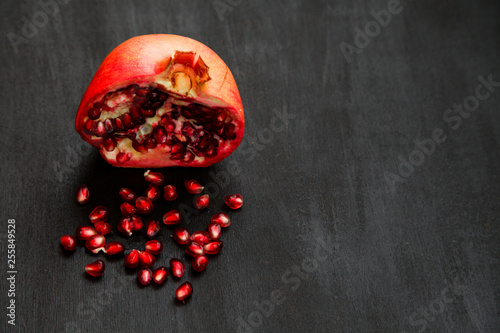 Ripe pomegranate berries in a bowl, on the black wooden, close up on 