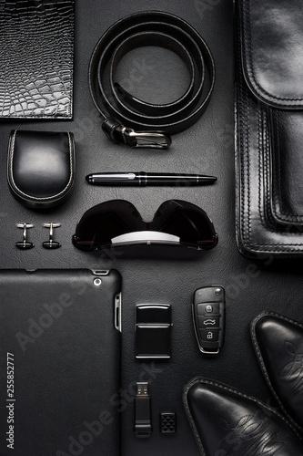 Man accessories in business style, briefcase, gadgets, shoes, clothes and other luxury businessman attributes on leather black background, fashion industry, top view