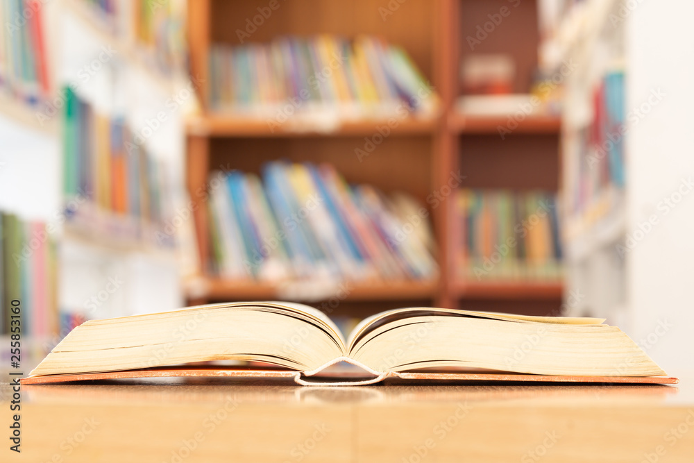 Book in library with old open textbook, stack piles of literature text archive on reading desk, and aisle of bookshelves in school study class room background for academic education learning concept Book in library with old open textbook, stack piles of literature text archive on reading desk, and aisle of bookshelves in school study class room background for academic education learning concept