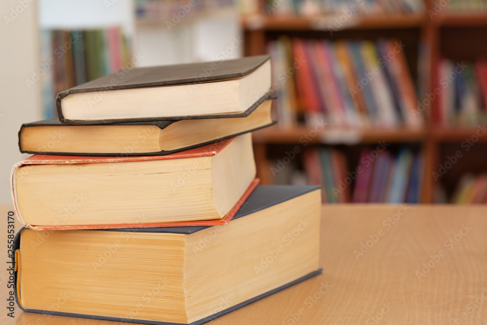 Book in library with old open textbook, stack piles of literature text archive on reading desk, and aisle of bookshelves in school study class room background for academic education learning concept Book in library with old open textbook, stack piles of literature text archive on reading desk, and aisle of bookshelves in school study class room background for academic education learning concept
