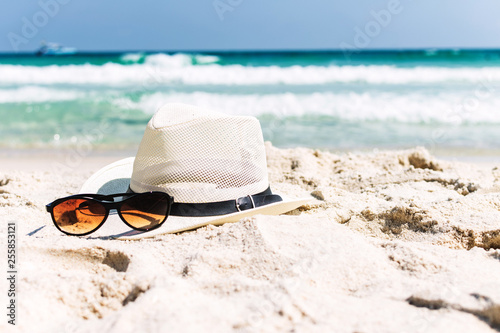 Close up straw hat and sunglasses  on tropical beach and white sandy background. Summer vacation concept. traveling and relax.