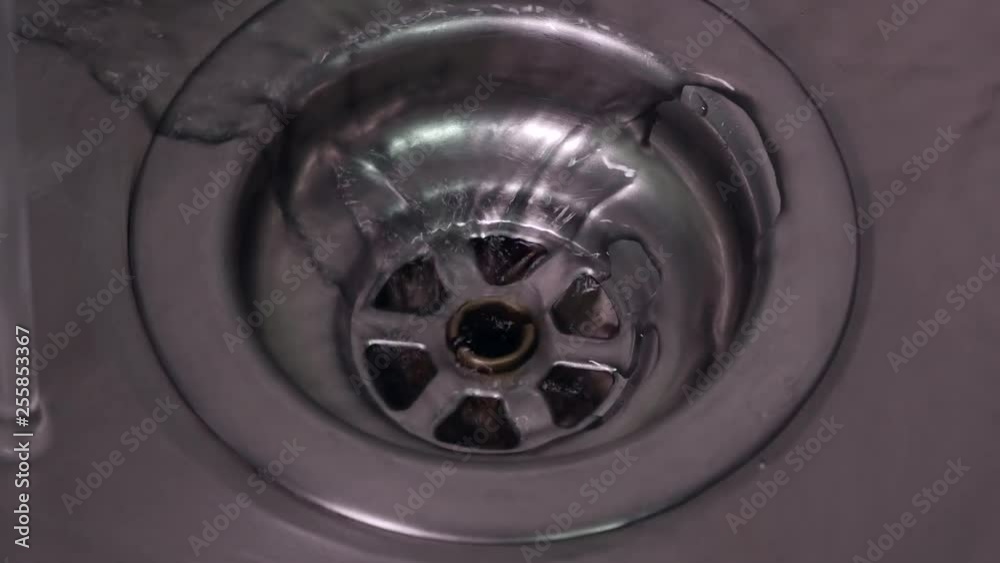 Fresh water running down plug hole in stainless steel sink. Close up, zoom in. Fresh water running down plug hole in stainless steel sink. Close up, zoom in.