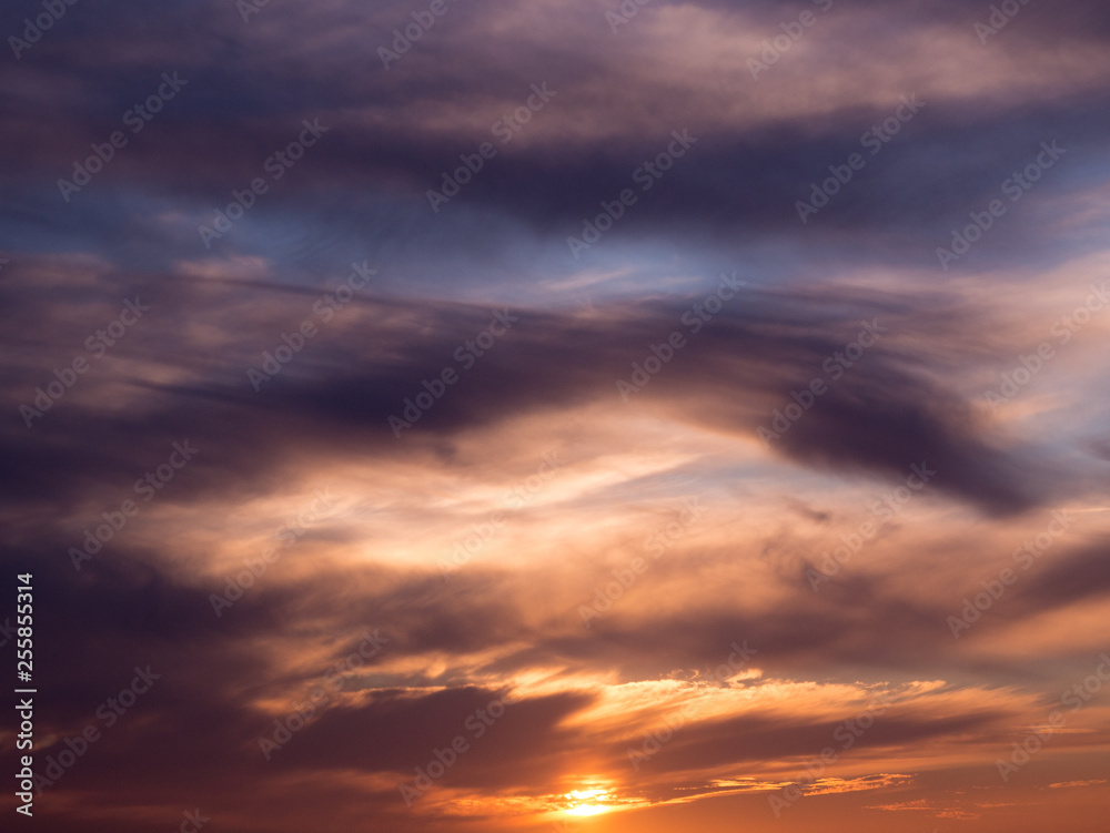 Dark dramatic clouds in sky at sunset with blue orange gradient