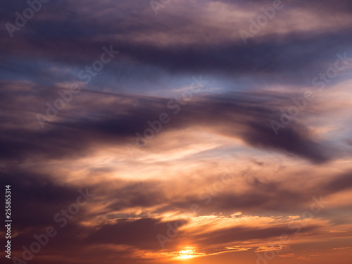 Dark dramatic clouds in sky at sunset with blue orange gradient © Barry
