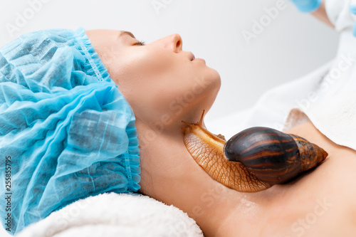 Young woman undergoing treatment with giant Achatina snails in beauty salon.