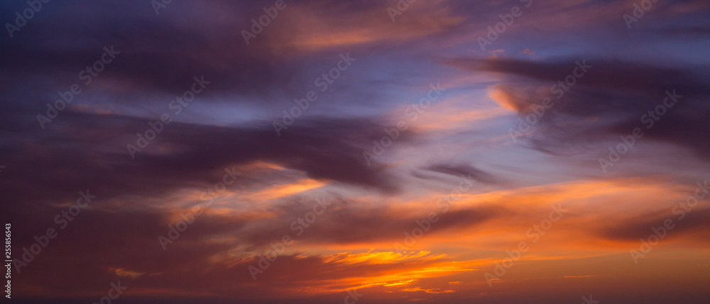 Wide angle view of dark dramatic clouds in sky at sunset with blue orange gradient