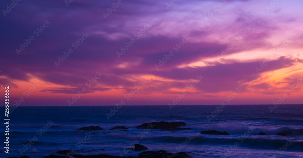 Beautiful long exposure shot over ocean at dusk just after sunset with red magenta gradient sky and dark waves below