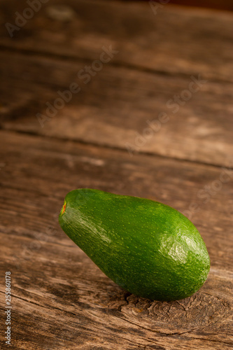 Shiny green avocado on wood