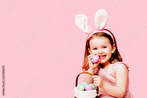 Portrait of a happy little toddler girl with easter bunny ears and a basket of eggs photo