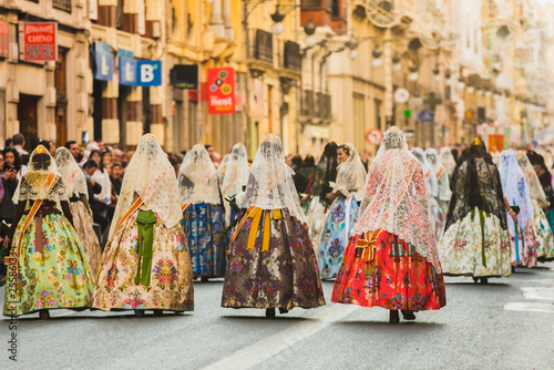 Several of the thousands of women Falleras who parade down the street of La Paz with their typical Valencian Spanish dresses during the offering of Fallas to the Virgin, seen from behind. photo