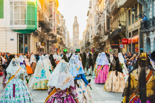 Several of the thousands of women Falleras who parade down the street of La Paz with their typical Valencian Spanish dresses during the offering of Fallas to the Virgin, seen from behind.