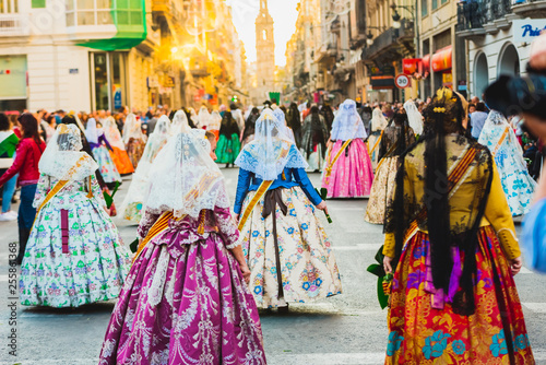Several of the thousands of women Falleras who parade down the street of La Paz with their typical Valencian Spanish dresses during the offering of Fallas to the Virgin, seen from behind. photo