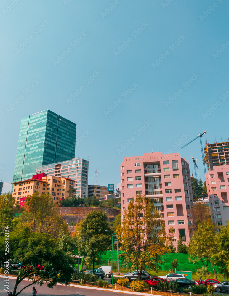 Full shot view of a part of Mexico city located in Santa Fé. includes corporate buildings and apartments surrounded by trees on blue sky