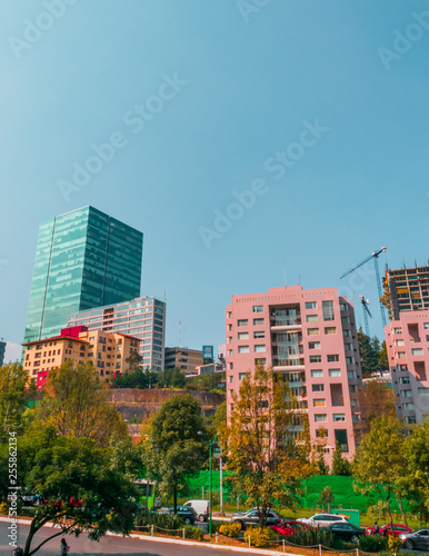 Full shot view of a part of Mexico city located in Santa Fé. includes corporate buildings and apartments surrounded by trees on blue sky