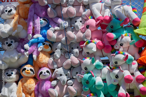 Stuffed animal toys at a fair as prizes hanging on mass on a wall.
