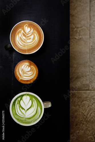 A cup of green tea matcha latte and cup of latte art coffee on wooden background