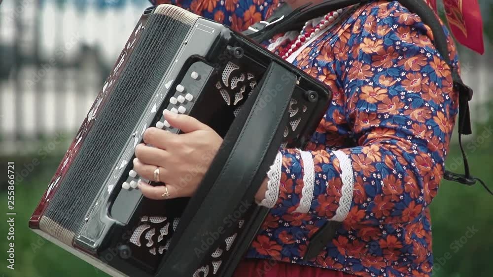 Woman, dressed in a folk costume, plays the accordion. Close up.