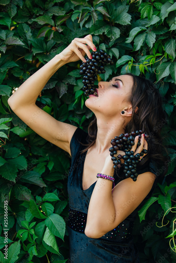 Portrait of young sexy brunette biting black grapes. Portrait of young sexy brunette biting black grapes.